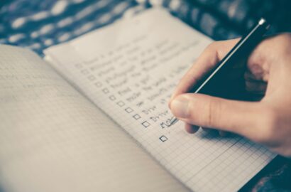 person writing bucket list on book